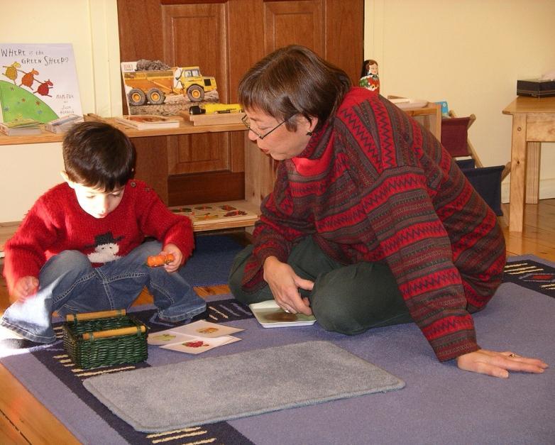 A Montessori guide working with a child on a floor mat